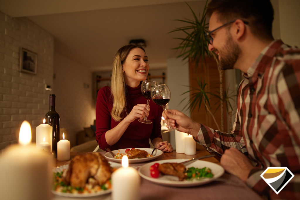 Beautiful couple having romantic dinner with candles and red wine at home